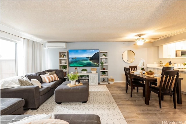 living area with a wall mounted air conditioner, a textured ceiling, wood finished floors, and ceiling fan