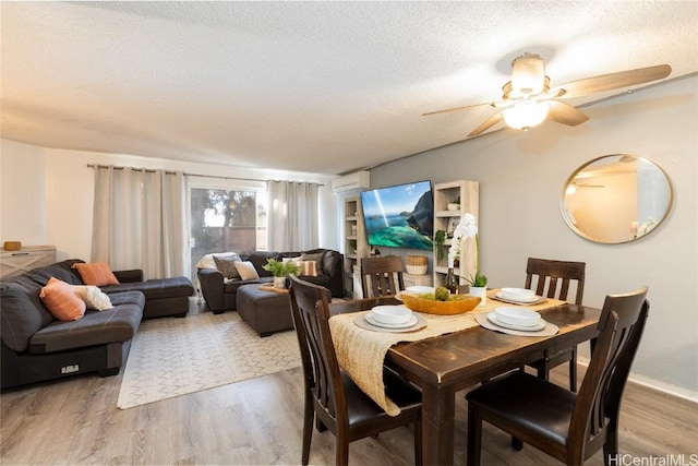 dining space featuring a wall mounted air conditioner, a textured ceiling, and wood finished floors