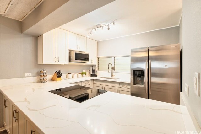 kitchen with light stone countertops, a sink, stainless steel appliances, white cabinets, and rail lighting