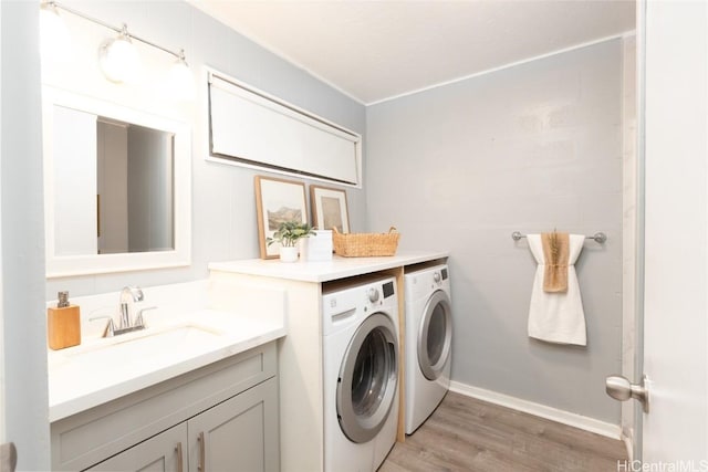 washroom with laundry area, independent washer and dryer, light wood-type flooring, and a sink