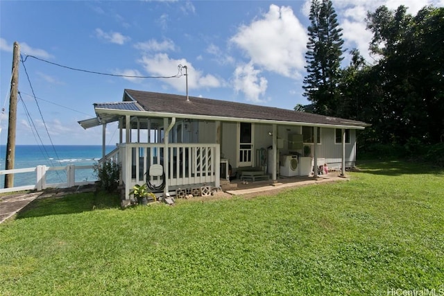 back of house featuring fence, washer / clothes dryer, a lawn, and a water view