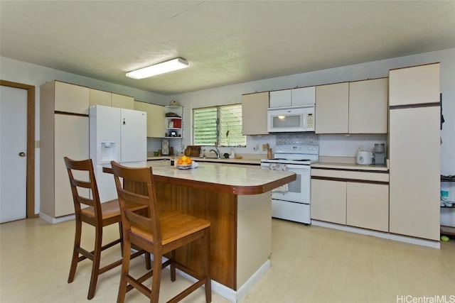 kitchen featuring white appliances, light floors, a kitchen island, light countertops, and a kitchen bar