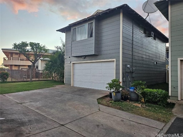 property exterior at dusk featuring concrete driveway, an attached garage, and fence