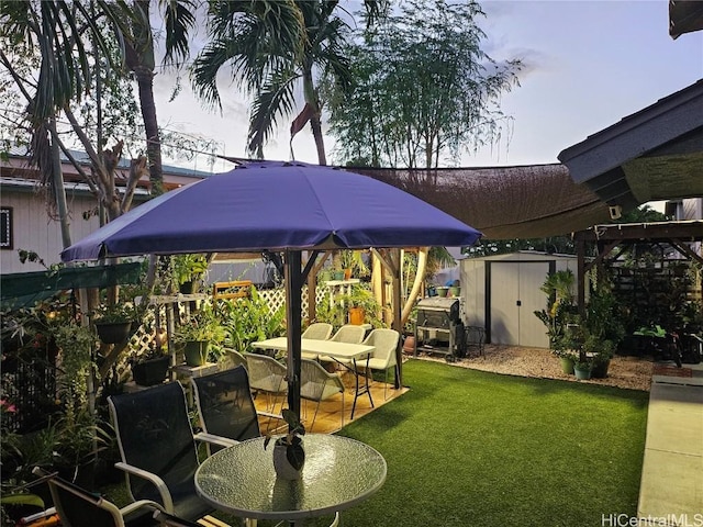 view of yard featuring a patio area, an outbuilding, outdoor dining space, and a shed