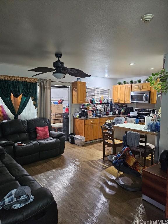 living room with light wood-style floors, ceiling fan, and a textured ceiling