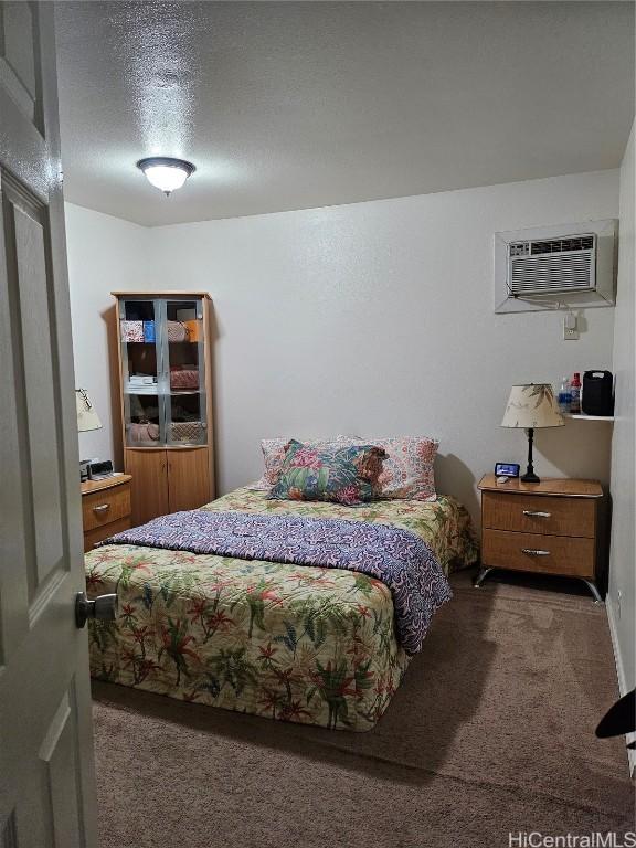 bedroom with a textured ceiling, carpet, and a wall mounted AC