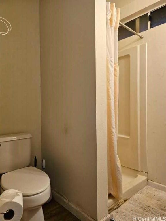 full bathroom with a shower stall, toilet, wood finished floors, and baseboards