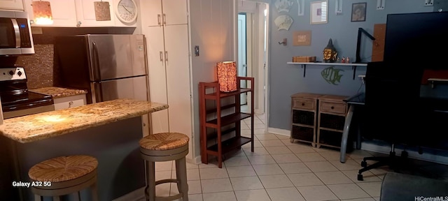 423 Kaiolu St Unit 106, Honolulu, HI 96815 - kitchen featuring stainless steel appliances, white cabinets, light tile patterned flooring, backsplash, and a breakfast bar