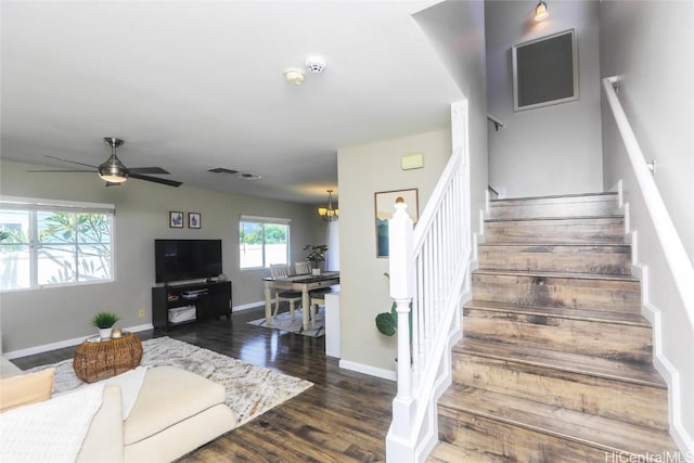 staircase featuring ceiling fan with notable chandelier, wood finished floors, and baseboards