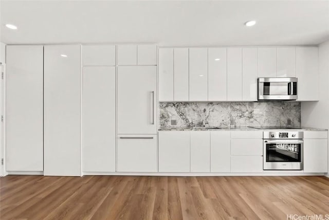 kitchen featuring light wood-type flooring, stainless steel appliances, modern cabinets, and white cabinets