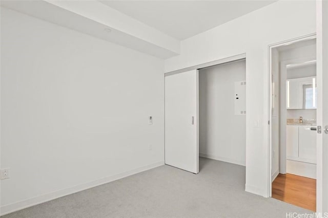 unfurnished bedroom featuring baseboards, a closet, and light carpet