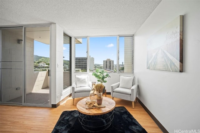 living area with a wealth of natural light, a textured ceiling, and wood finished floors