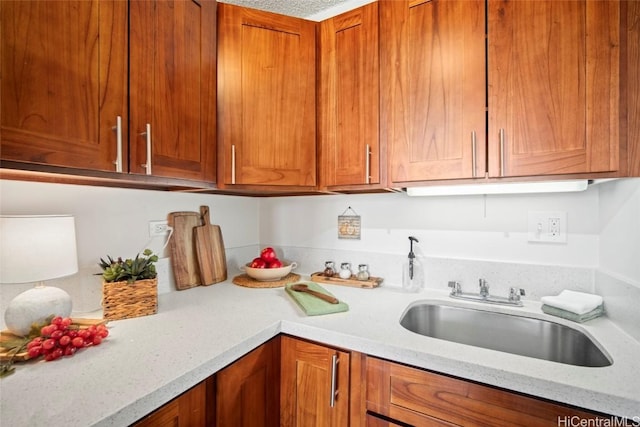 kitchen with light stone counters, brown cabinets, and a sink