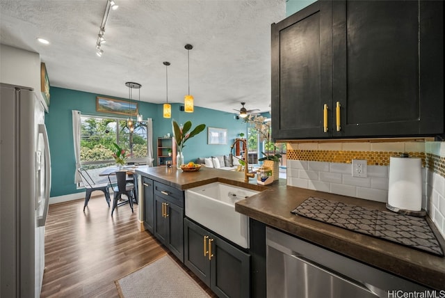 kitchen with a sink, a textured ceiling, wood finished floors, freestanding refrigerator, and decorative backsplash