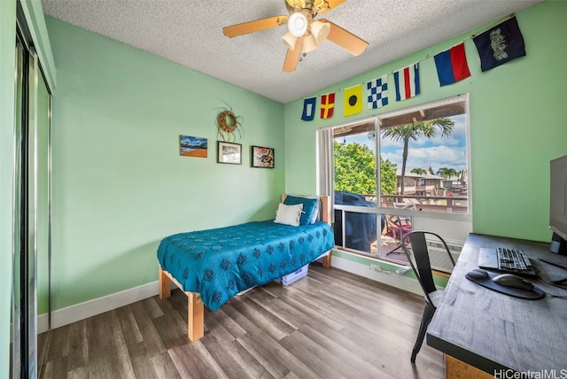 bedroom featuring ceiling fan, baseboards, a textured ceiling, and wood finished floors