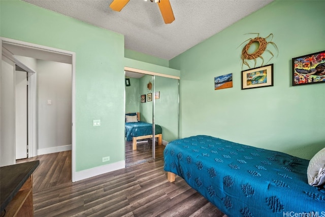 bedroom with a closet, a textured ceiling, baseboards, and wood finished floors