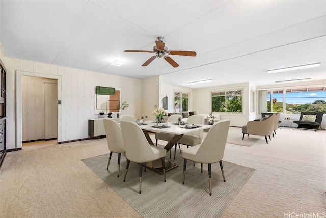 dining area with a ceiling fan and light carpet