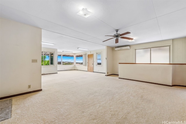 below grade area featuring a ceiling fan, carpet, baseboards, and a wall mounted air conditioner