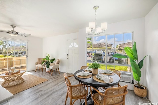 dining space featuring ceiling fan with notable chandelier, cooling unit, and wood finished floors