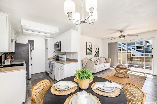 dining space with electric panel, dark wood finished floors, and ceiling fan with notable chandelier