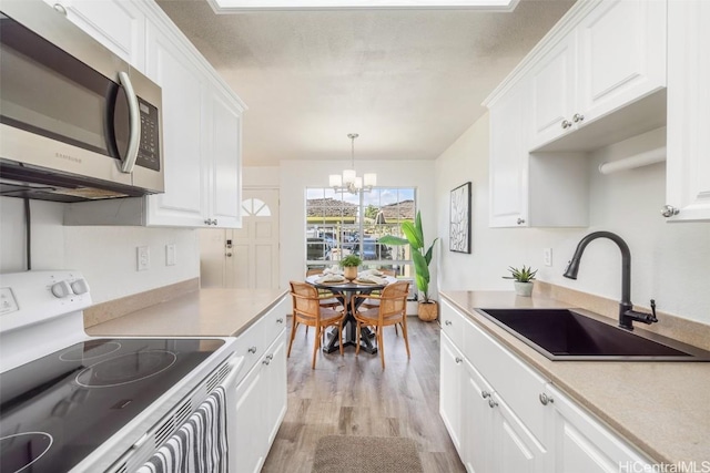 kitchen with electric stove, a sink, stainless steel microwave, white cabinetry, and light wood-style floors