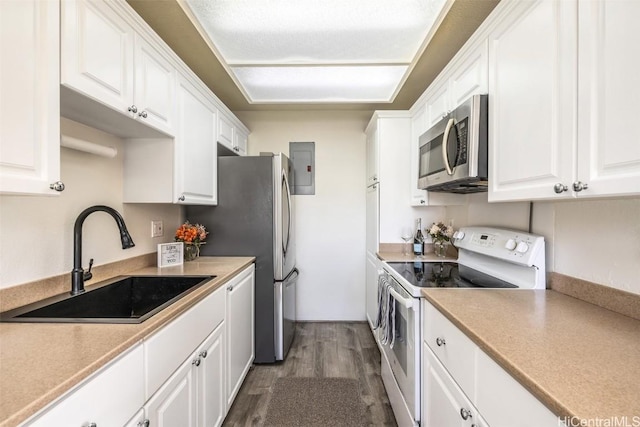 kitchen with a sink, appliances with stainless steel finishes, white cabinets, light countertops, and dark wood-style flooring