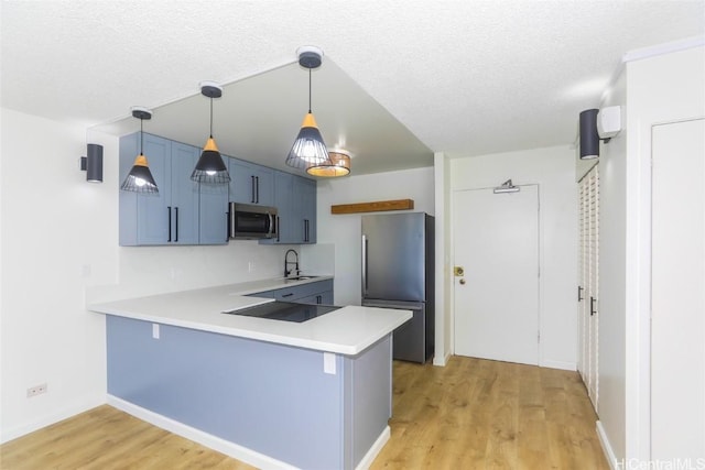 kitchen with light wood-style floors, appliances with stainless steel finishes, light countertops, and a peninsula