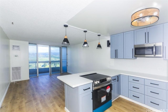 kitchen with visible vents, a peninsula, light wood-style flooring, light countertops, and appliances with stainless steel finishes