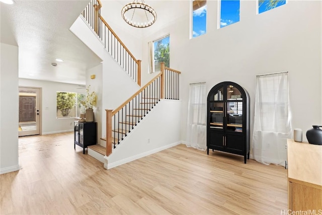 foyer entrance with light wood finished floors, a high ceiling, stairs, and baseboards