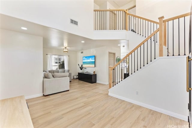 living room with a high ceiling, wood finished floors, visible vents, and baseboards