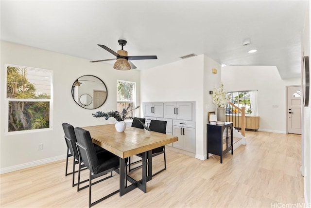 dining space featuring a wealth of natural light, light wood-style flooring, stairs, and baseboards