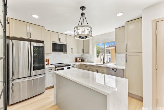 kitchen with tasteful backsplash, appliances with stainless steel finishes, light wood-style floors, and a sink