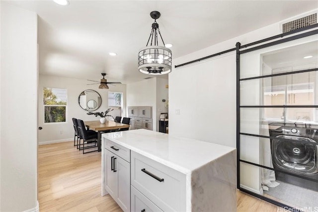 kitchen with visible vents, washer / dryer, light countertops, and light wood finished floors