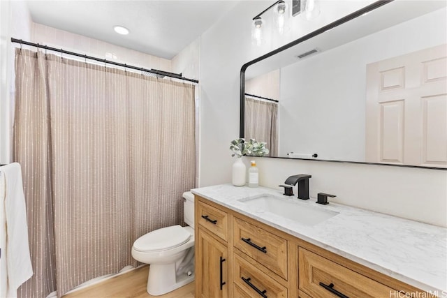 bathroom with vanity, toilet, wood finished floors, and visible vents