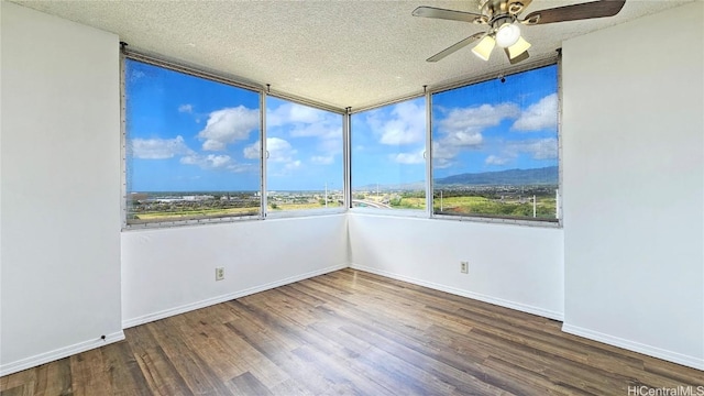 spare room with ceiling fan, baseboards, a textured ceiling, and wood finished floors