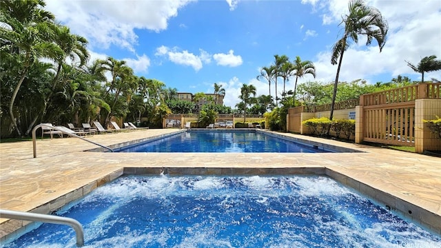 pool with a patio, a community hot tub, and fence