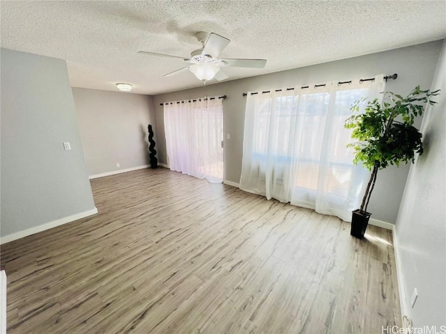 empty room with baseboards, a textured ceiling, wood finished floors, and a ceiling fan