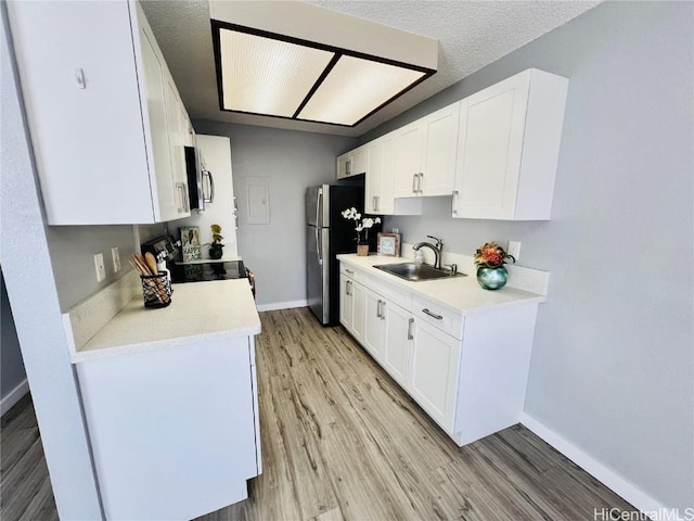 kitchen featuring light wood-style flooring, appliances with stainless steel finishes, light countertops, and a sink