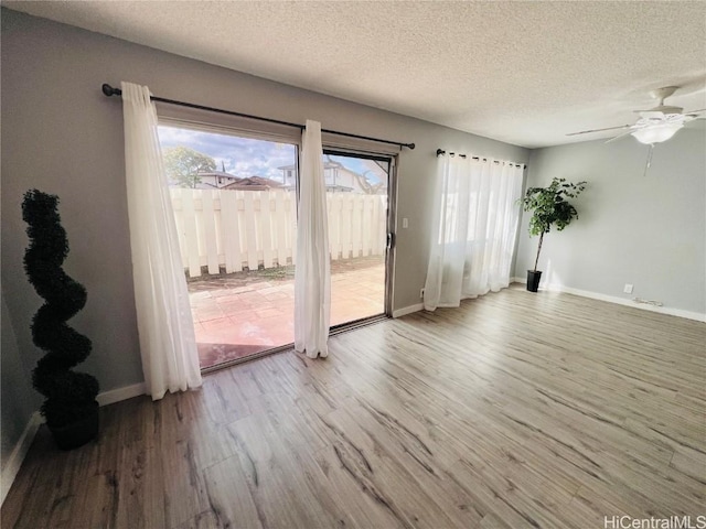 spare room featuring baseboards, a textured ceiling, wood finished floors, and a ceiling fan