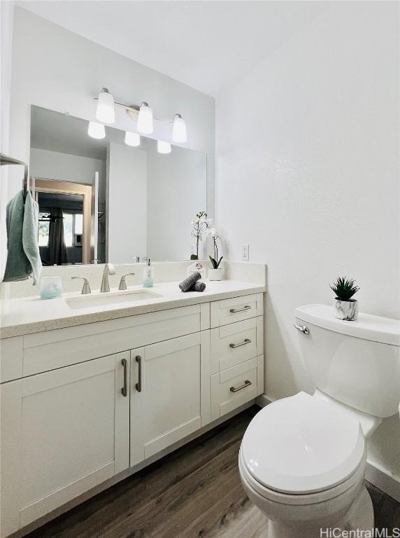 bathroom with toilet, wood finished floors, and vanity