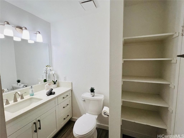 bathroom with visible vents, toilet, wood finished floors, baseboards, and vanity