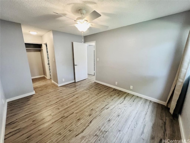 unfurnished bedroom featuring a closet, baseboards, a textured ceiling, and wood finished floors