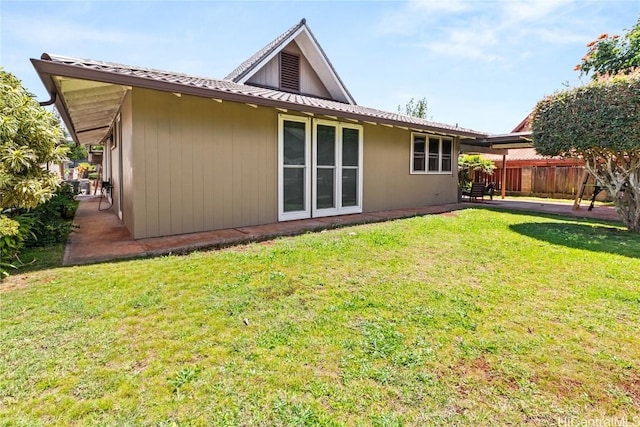 rear view of house with a patio area, a lawn, and fence