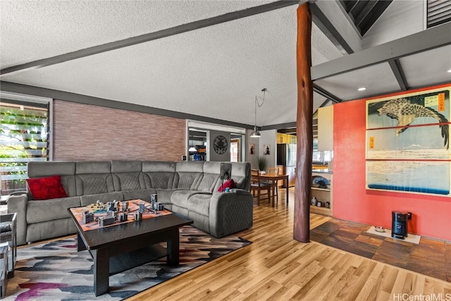 living area featuring beamed ceiling, a textured ceiling, and wood finished floors