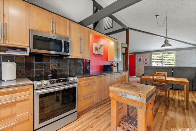 kitchen featuring light wood-style flooring, tasteful backsplash, dark countertops, stainless steel appliances, and vaulted ceiling