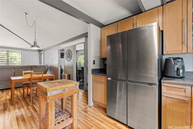 kitchen with light wood finished floors, freestanding refrigerator, vaulted ceiling, a textured ceiling, and dark countertops