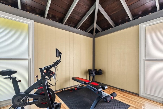 workout room featuring lofted ceiling, wood ceiling, wood finished floors, and wood walls