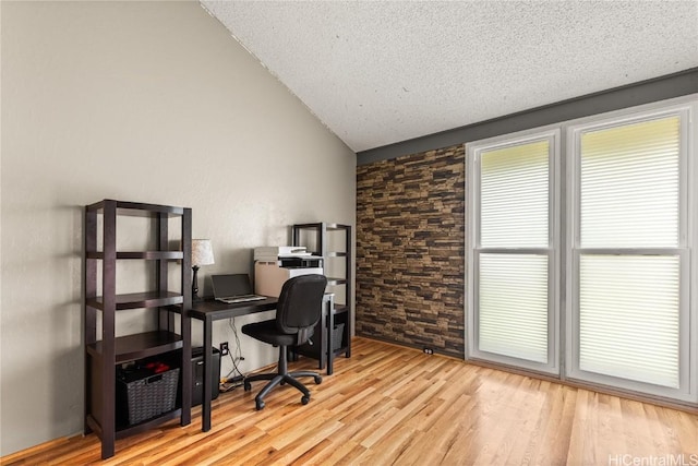 office area featuring vaulted ceiling, wood finished floors, and a textured ceiling