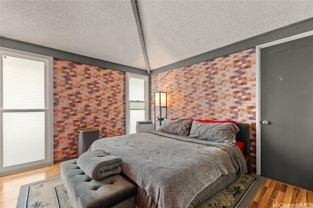 bedroom featuring a textured ceiling, wood finished floors, and vaulted ceiling