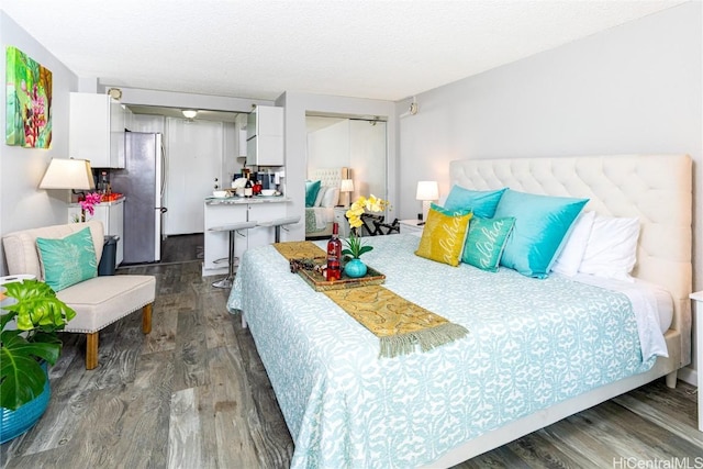 bedroom featuring dark wood-style floors, a closet, freestanding refrigerator, and a textured ceiling